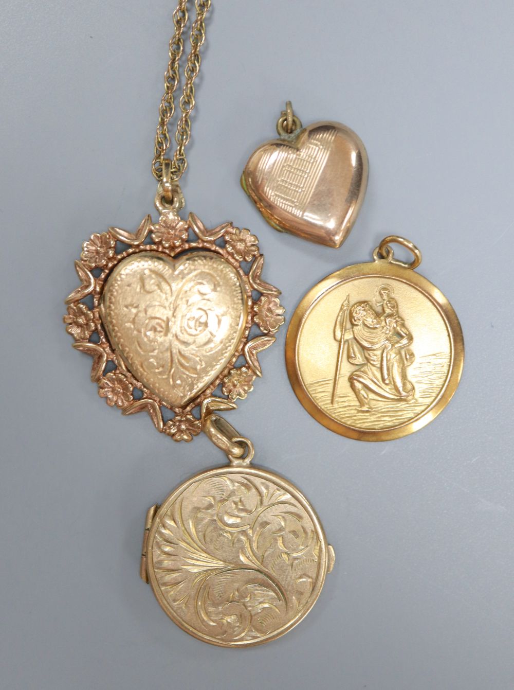 A 9ct gold heart-shaped fancy locket on chain, an engraved circular locket, a small heart-shaped locket and a St Christopher medallion